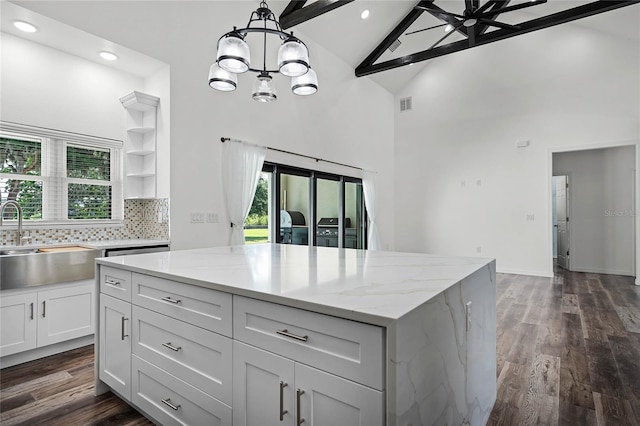 kitchen featuring dark wood finished floors, backsplash, a sink, and a center island