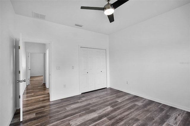 unfurnished bedroom featuring dark wood-type flooring, a closet, visible vents, and baseboards