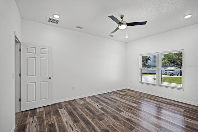 empty room with dark wood-style floors, baseboards, visible vents, and a textured ceiling