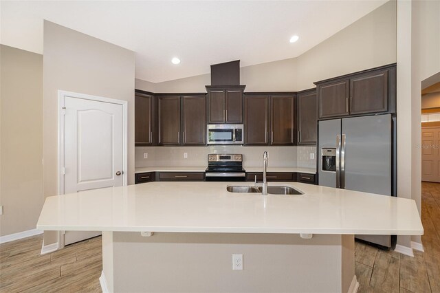 kitchen with dark brown cabinetry, a sink, stainless steel appliances, light countertops, and backsplash