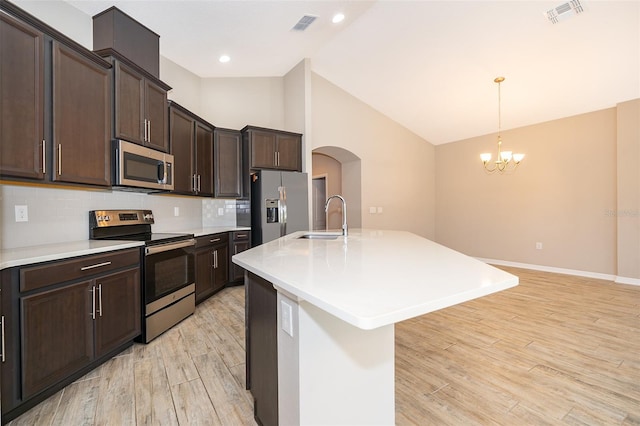 kitchen with arched walkways, stainless steel appliances, visible vents, a sink, and light wood-type flooring