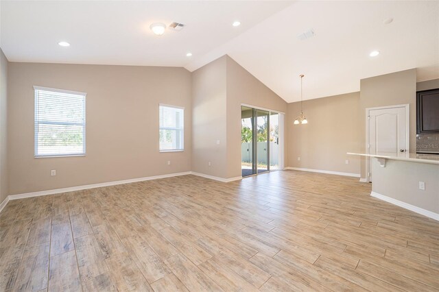 unfurnished living room featuring light wood-type flooring, baseboards, visible vents, and vaulted ceiling