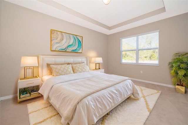 bedroom featuring carpet floors, a raised ceiling, and baseboards