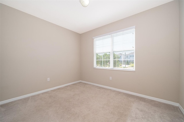 empty room featuring baseboards and light colored carpet