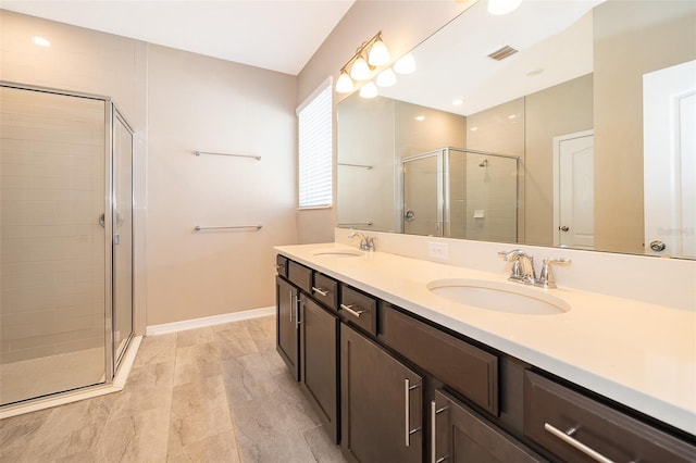 bathroom featuring double vanity, a shower stall, visible vents, and a sink