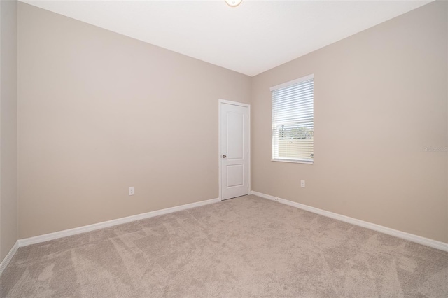 unfurnished room featuring light carpet and baseboards