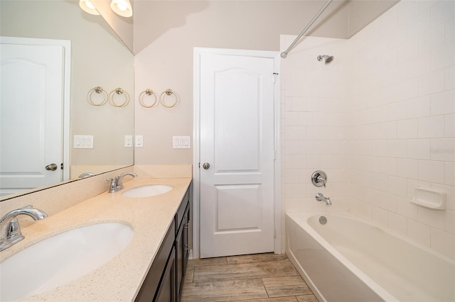 full bathroom with double vanity, tub / shower combination, a sink, and wood finished floors