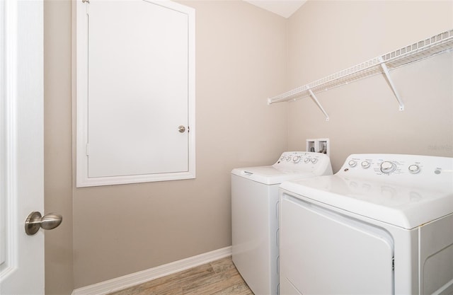 laundry area featuring light wood-style floors, laundry area, washer and clothes dryer, and baseboards