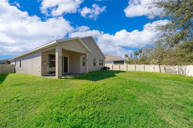 back of property with a fenced backyard, a lawn, and stucco siding