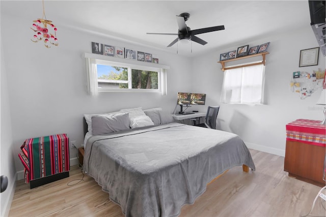 bedroom featuring multiple windows, baseboards, and wood finished floors