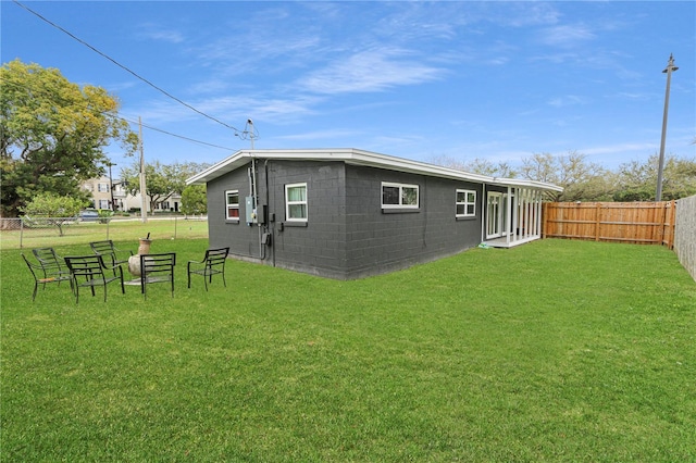 exterior space featuring a yard, a fenced backyard, and concrete block siding