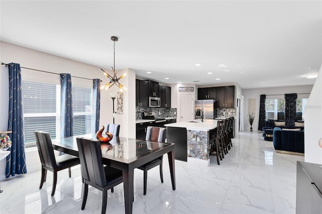 dining space featuring a chandelier, recessed lighting, and marble finish floor