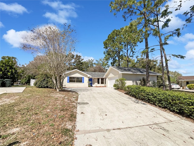 single story home featuring a garage, driveway, and stucco siding