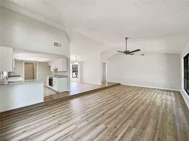 unfurnished living room with vaulted ceiling, visible vents, and a sink