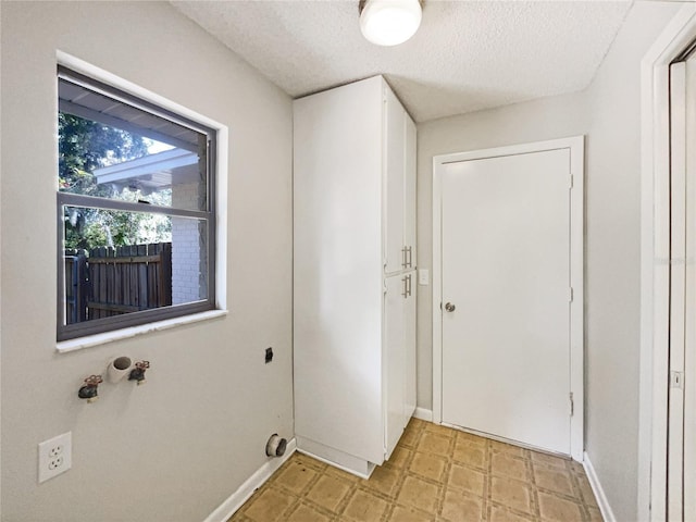 washroom with a textured ceiling, hookup for an electric dryer, laundry area, baseboards, and light floors