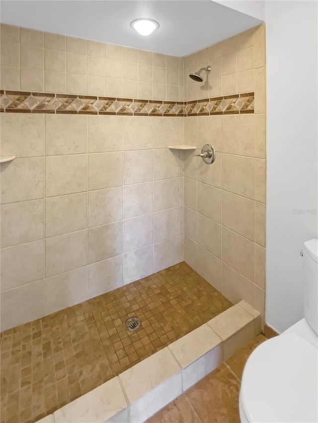 bathroom featuring tiled shower and toilet