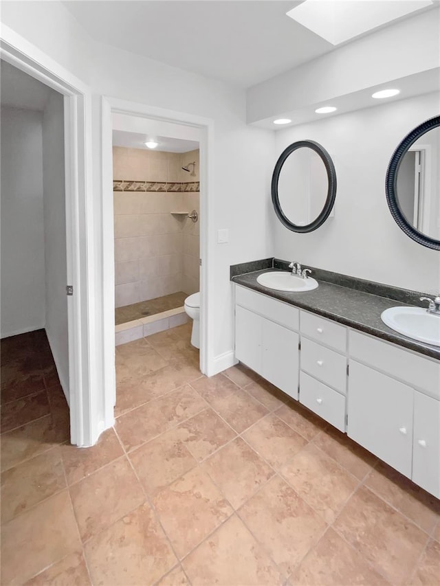 bathroom with double vanity, walk in shower, a skylight, and a sink