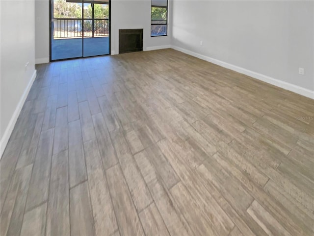 unfurnished living room featuring a fireplace, baseboards, and wood finished floors