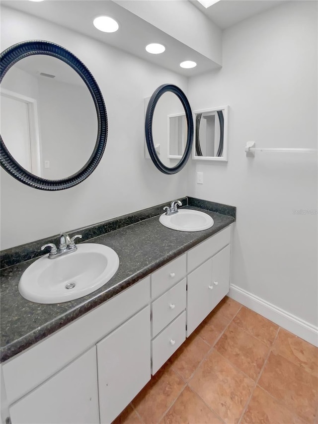 full bathroom with double vanity, tile patterned flooring, baseboards, and a sink