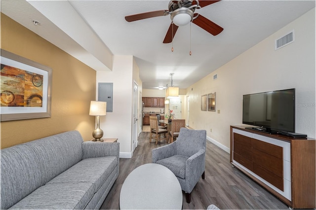 living room with baseboards, dark wood finished floors, visible vents, and electric panel