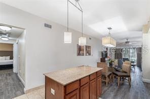 kitchen featuring a ceiling fan, a kitchen island, hanging light fixtures, vaulted ceiling, and light countertops