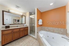 bathroom featuring tile patterned flooring, a jetted tub, vanity, and a shower stall