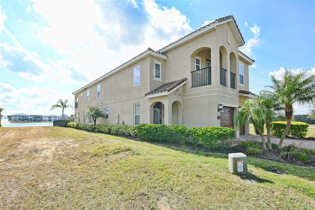 view of front of home with a tiled roof, a front lawn, and stucco siding