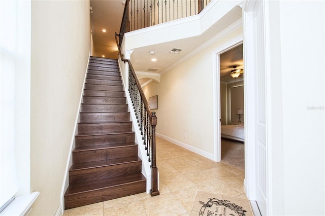 staircase with visible vents, a high ceiling, ornamental molding, baseboards, and tile patterned floors