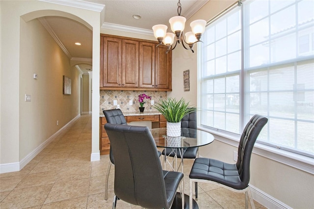 dining room featuring arched walkways, crown molding, baseboards, and an inviting chandelier