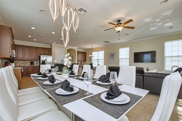 dining room featuring ceiling fan with notable chandelier, visible vents, crown molding, and light tile patterned floors