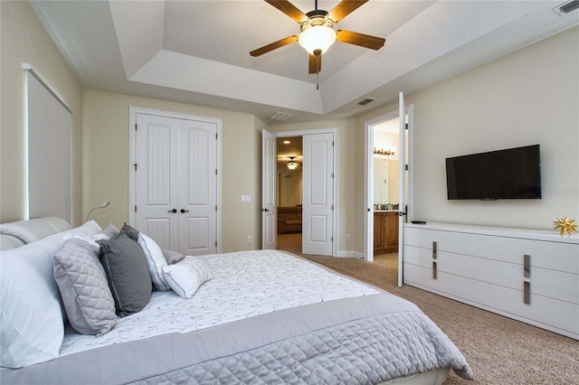 bedroom featuring light colored carpet, visible vents, baseboards, a closet, and a raised ceiling