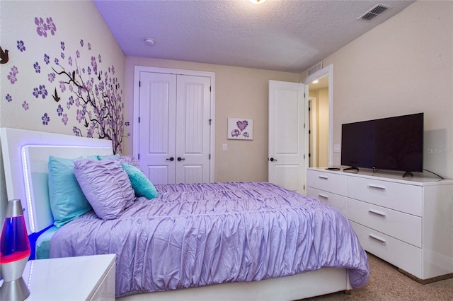 carpeted bedroom with a textured ceiling, visible vents, and a closet