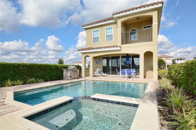 back of property featuring a patio, a balcony, a tiled roof, fence, and stucco siding