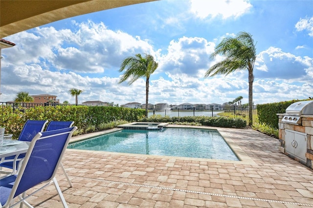 view of pool featuring a patio, an outdoor kitchen, fence, a pool with connected hot tub, and a grill