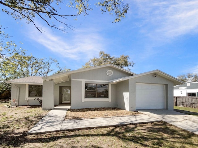 view of front of home featuring driveway, an attached garage, fence, and stucco siding