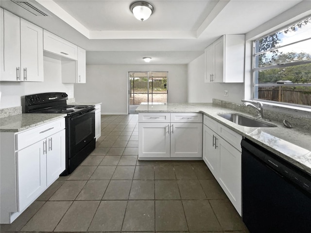 kitchen with white cabinets, a peninsula, a tray ceiling, black appliances, and a sink