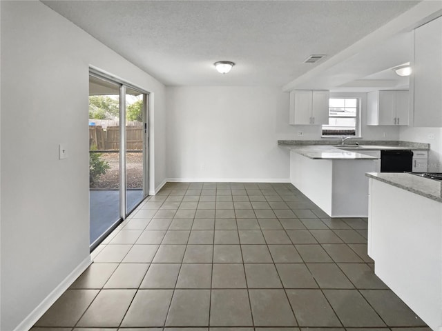 kitchen with black dishwasher, tile patterned floors, a peninsula, a textured ceiling, and white cabinetry