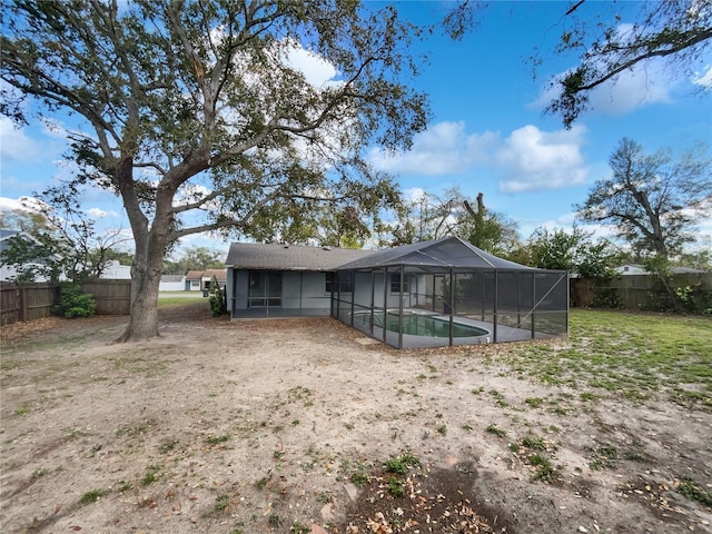 rear view of house with a fenced in pool, glass enclosure, and a fenced backyard