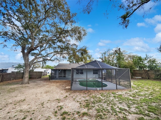 rear view of house featuring glass enclosure and a fenced backyard