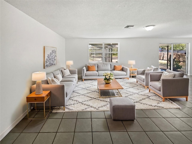 living room with a healthy amount of sunlight, visible vents, a textured ceiling, and tile patterned floors