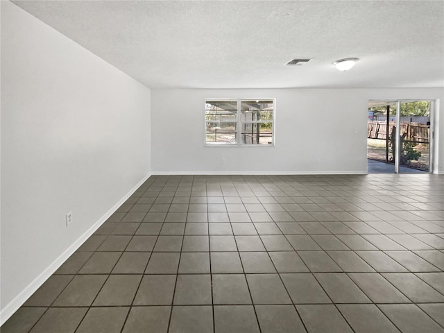 empty room with visible vents, a textured ceiling, baseboards, and tile patterned floors