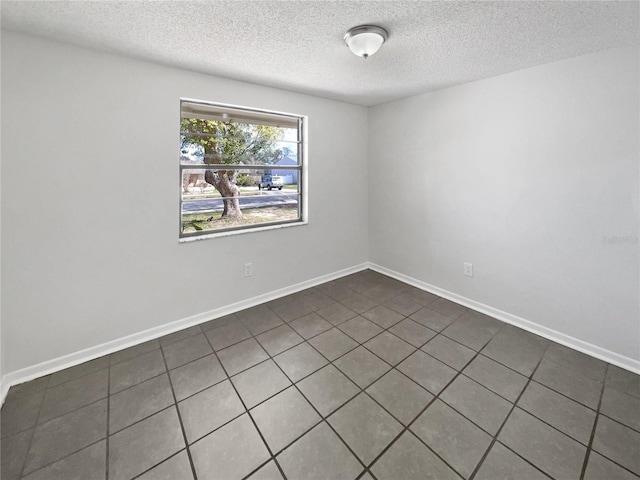 spare room featuring a textured ceiling and baseboards