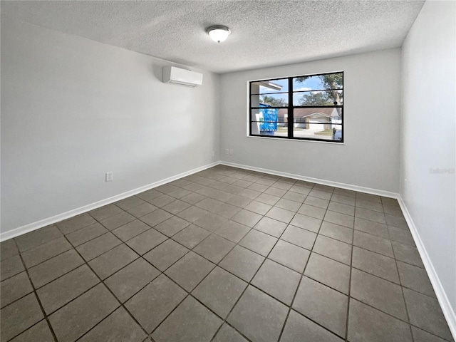 empty room featuring an AC wall unit, a textured ceiling, and baseboards