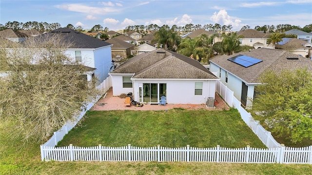 rear view of house featuring central AC unit, a fenced backyard, a lawn, a residential view, and stucco siding