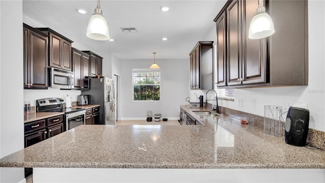 kitchen with stainless steel appliances, a sink, dark brown cabinetry, and light stone countertops