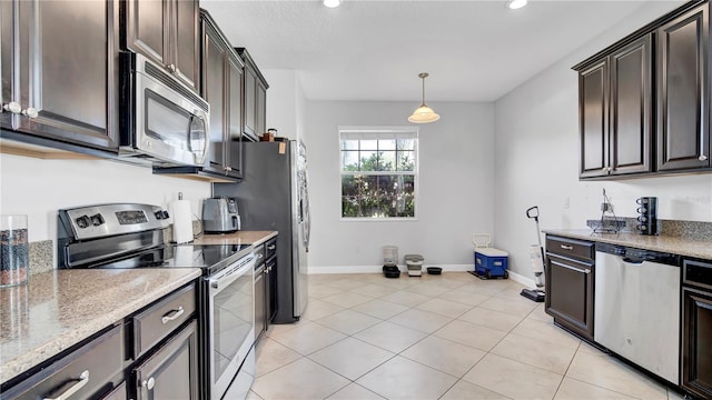 kitchen with dark brown cabinetry, light tile patterned floors, baseboards, appliances with stainless steel finishes, and light stone counters