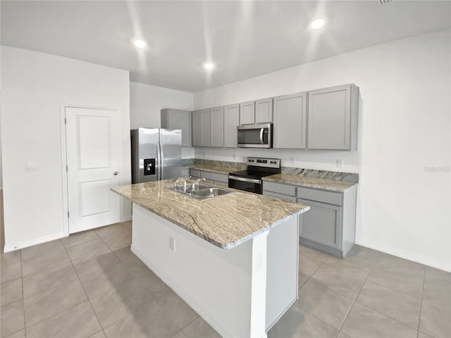 kitchen featuring appliances with stainless steel finishes, gray cabinets, a sink, and light stone countertops