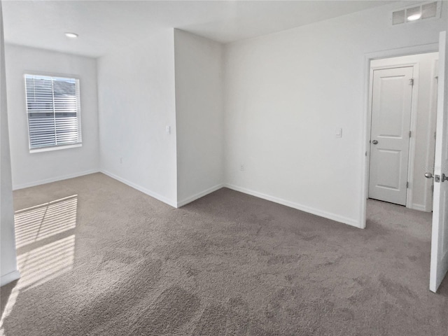 spare room with carpet, visible vents, and baseboards