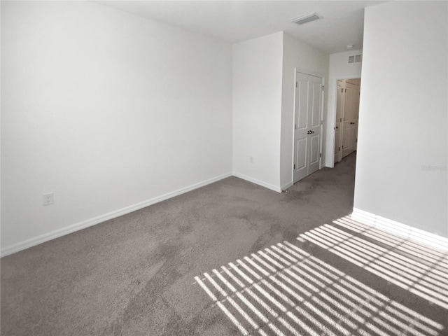 empty room with visible vents, baseboards, and carpet flooring