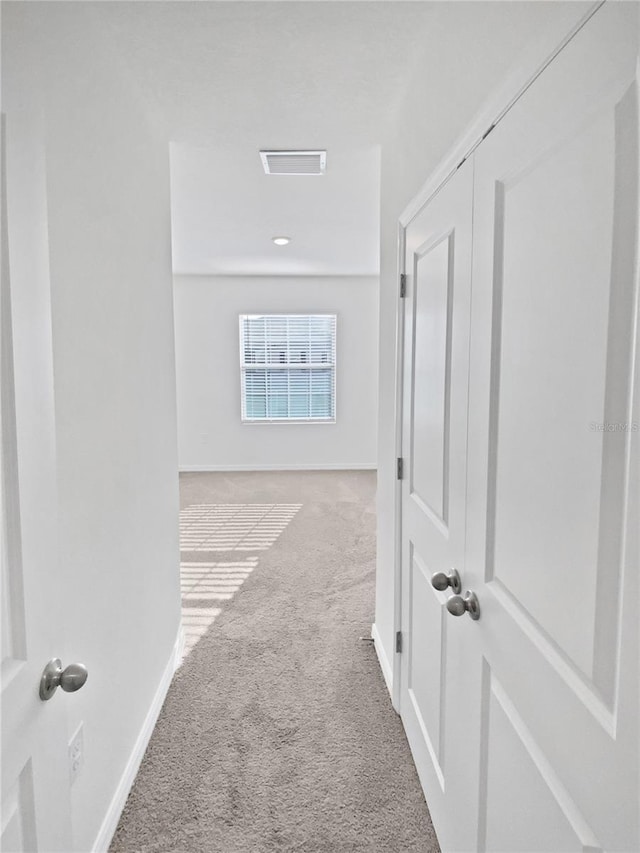 hallway featuring carpet flooring, visible vents, and baseboards